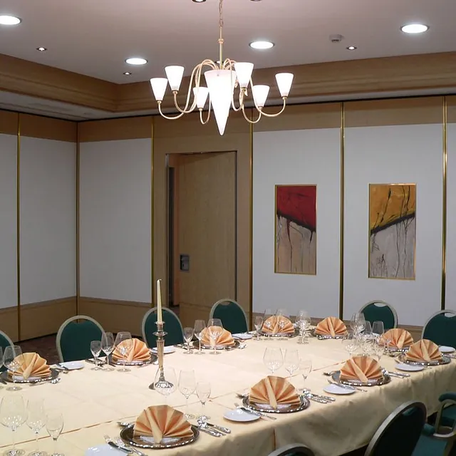 Flexible DORRflex-Trennwand in einem Besprechungsraum mit dekorativen Wandbildern und elegantem Tischarrangement.